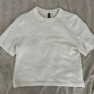 Stickad kortärmad  - Superfin vit stickad tröja från Divided, H&M. Modellen är boxig med korta ärmar och ribbade detaljer vid hals, ärmslut och nederkant. Perfekt till jeans eller kjol för en clean och chill look.