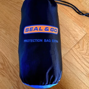 Seal & Go reseskydd till barnvagn - Reseskydd från Seal & Go, perfekt för att skydda din barnvagn/packning på resan. Tillverkad i slitstark syntet med dragkedja och praktiskt handtag. Logga i orange och blått på sidan. Enkel att packa ihop och ta med sig. Köpt för 999kr. Säljer billigt pga slitningar i botten - går säkert att sätta silvertejp eller liknande, kraftigt material så krävs mycket för att bagen ska gå sönder. Kan skicka bilder med mått samt bilder på slitningarna under.