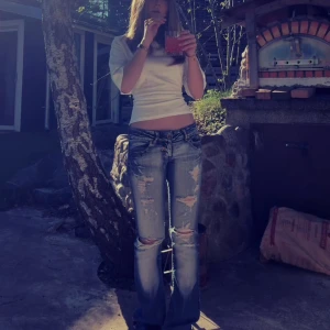 Low waist Crazy age jeans  - Säljer ett par lågmidjade jeans med bootcut passform och slitna detaljer på både fram- och baksida. Jeansen har klassiska fem fickor, snygga slitningar vid knäna och coola broderier på bakfickorna.❤️ Har laggat lite på insidan där back så kontakte vid intresse av att se bild på det om det skulle önskas!❤️Kontakta mig vid bättre bilder!❤️