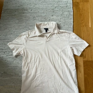 Beige pikétröja från H&M - Snygg beige pikétröja från H&M i regular fit. Klassisk krage och korta ärmar, perfekt för en clean och avslappnad stil. Tillverkad i mjuk bomull som känns skön mot huden. Enkel att matcha med jeans eller shorts för en fräsch look.