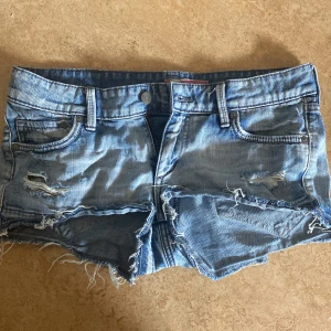 Ljusblå jeansshorts från NOW - Säljer ett par ljusblå jeansshorts från NOW med slitna detaljer och fransar nertill. 