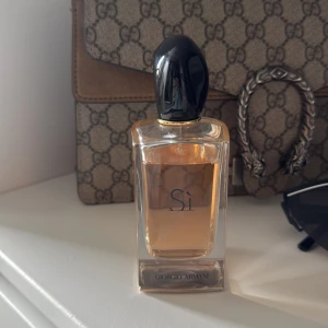 Giorgio Armani Sì Eau de Parfum - Elegant parfymflaska med svart lock och transparent glas som visar den ljusrosa vätskan. Sì från Giorgio Armani är en klassisk och feminin doft, perfekt för dig som gillar lyxiga och tidlösa parfymer.