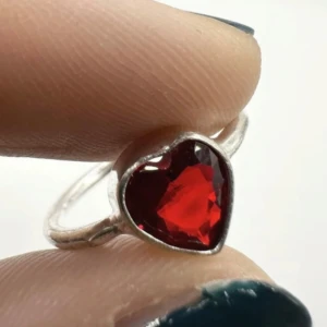 Silverring med granat i hjärtform – symbol för kärlek, mod & styrka - Vacker handgjord ring med hjärtformad granat i intensivt röd nyans, infattad i silverpläterad metall. Enkel och känslostark design – passar perfekt för dig som gillar smycken med betydelse. I mycket gott skick och med innermått på ca 17 mm. Granat står traditionellt för kärlek, mod och passion. Ingen prutning – men jag erbjuder gärna bundlerabatt vid köp av flera smycken.  