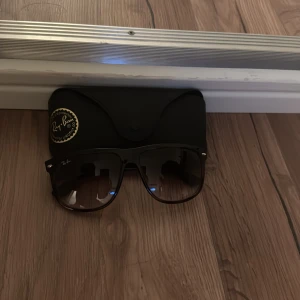  Ray-Ban Boyfriend - Snygga solglasögon från Ray-Ban med brun båge och bruna tonade glas. Klassisk fyrkantig form och diskret logga på linsen. Kommer med originalfodral.