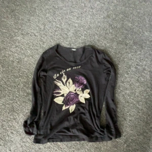 Tornadomart  - Rare tornadomart tröja med fett tryck av en blomma och text på ryggen. Passar unisex med en slim fit.