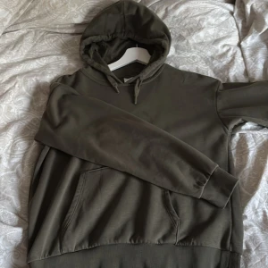 Olivgrön hoodie från Gina Tricot - Säljer en olivgrön hoodie från Gina Tricot med huva och känguruficka. Tröjan har långa ärmar, ribbade muddar och dragsko i huvan. Perfekt för en avslappnad stil. Använd 1-2 gånger. Pris kan diskuteras 