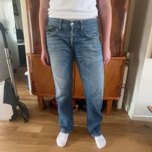 True Religion blå jeans slim fit - Säljer ett par blå jeans från True Religion med klassiska kontrastsömmar och snygga fickdetaljer bak. Modellen är slim fit med normal passform och raka ben. Jeansen har låg midja och är tillverkade i slitstarkt denimtyg.