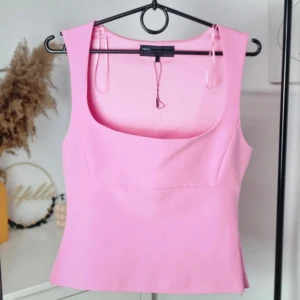 Rosa croppad linnetopp från zara - Säljer en söt rosa croppad linnetopp från zara med breda axelband och fyrkantig urringning. Perfekt för sommardagar och enkel att styla med jeans eller kjol.