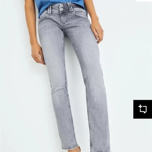 Grå jeansbyxor med raka ben - Säljer ett par grå jeansbyxor med raka ben och dubbla knappar i midjan. Byxorna har klassisk femficksdesign och är i en snygg tvättad grå färg. Perfekta till vardags med en enkel topp eller hoodie.