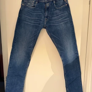 Blå Replay Rocco jeans herr - Snygga blå jeans från Replay, modell Rocco. Jeansen har normal midja och är tillverkade i mjukt denimtyg med stretch för extra komfort. Perfekta för en avslappnad och trendig look. Storlek 32/32
