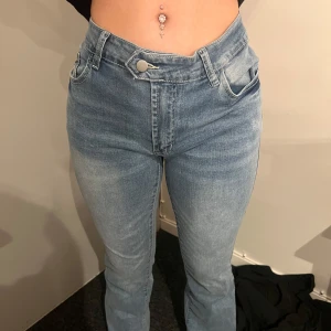 Ljusblå högmidjade jeans - Säljer ett par ljusblå jeans med hög midja och klassisk femficksdesign. Jeansen har raka ben och stängs med dragkedja och knapp. Perfekta till vardags och lätta att matcha med olika toppar.