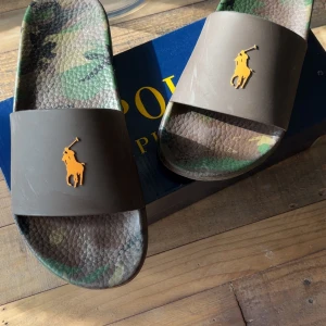 Polo Ralph lauren slides camo - Säljer ett par Slides från Polo Ralph lauren i storlek 43 men kan även passa 44, tofflorna är i ny skick använda ett par gånger perfekt nu inför sommaren inköpta för 1000kr svåra att hitta. Bara att skriva om ni har frågor osv kvitto finns .