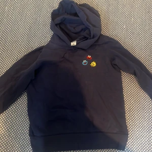 KAWS x Sesame Street hoodie & tröja - Tre tröjor från Uniqlo KAWS x Sesame Street-kollektionen. En marinblå hoodie med små broderade figurer, en vit hoodie med stort tryck av Sesame Street-karaktärer och en svart sweatshirt med KAWS-figurer. Alla har lång ärm och är i mjuk bomull. Hoodies for 600 kr st förutom dem svarta som du får för 275