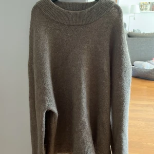 Beige stickad tröja från Gina Tricot - Mysig beige stickad tröja från Gina Tricot med bred ribbad krage. Perfekt för kyliga dagar och enkel att matcha med olika outfits. Klassisk modell med lång ärm och mjukt material.