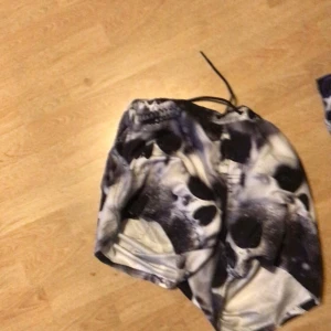 Svartvita shorts med dödskallemönster - Coola shorts med svartvita dödskallar och snörning i midjan. Perfekta för dig som vill sticka ut med en unik stil. Lätta och bekväma att bära, passar bra till sommarens alla äventyr.