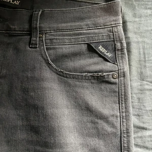 Grå jeans från Replay - Snygga grå jeans från Replay med klassisk femficksdesign. De har en diskret Replay-logga på bakfickan och en bekväm passform. Perfekta för en stilren look. Replay Anbass 