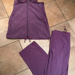 Lila fritidssett - Säljer en lila sett. Jackan har dragkedja och huva. Byxorna har en enkel design med dragsko i midjan.