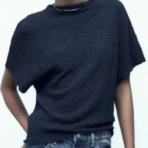 Mörkblå topp med textur - Snygg mörkblå topp med unik textur. Perfekt för en stilren look. Den har korta ärmar och en avslappnad passform. Passar bra till jeans eller kjol för en trendig outfit.