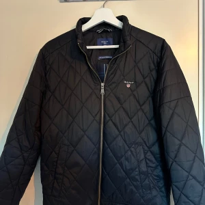 Blå jacka från GANT - Snygg  quiltad jacka från GANT. Insidan har ett stilrent rutigt mönster i blått och vitt. Nypris ca 1999. Storlek S