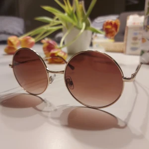 Runda solglasögon från H&M - Snygga runda solglasögon från H&M med metallbågar och bruna tonade glas. Perfekta för en retro look och skyddar mot solen med stil. Passar både till stranden och stan. Skriv om ni har någon fundering!✨️