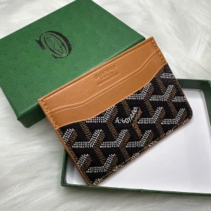 Brun och svart kortfodral  - Säljer ett stilrent kortfodral  i brunt och svart med ett ikoniskt mönster. Fodralet har flera kortfack och en snygg gul insida. Perfekt för att hålla dina kort organiserade med stil.