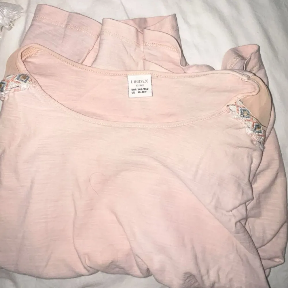 Säljer en ljusrosa topp från Lindex med fina spetsdetaljer vid axlarna. Toppen är ärmlös och har en mjuk och bekväm passform. Perfekt för en avslappnad stil. Hör av dig vid intresse! 🌸. Yläosat.