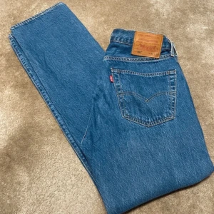 Levis 501 jeans - Klassiska Levis 501 jeans i blå denim. Dessa jeans har en rak passform och är tillverkade av högkvalitativt jeansmaterial. Perfekta för en tidlös stil.