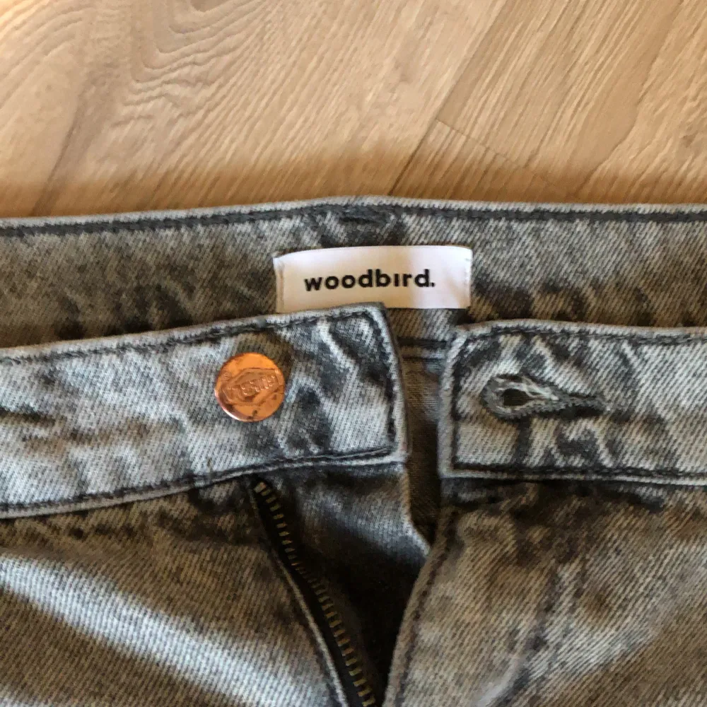 Snygga grå jeans från Woodbird med en klassisk femficksdesign. De har en dragkedja och knapp framtill samt en läderpatch med logotypen på baksidan. Perfekt tillskott för garderoben!👍. Farkut & Housut.