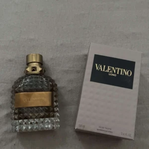 Valentino Uomo Eau de Toilette - Säljer en elegant Valentino Uomo Eau de Toilette. Flaskan har en lyxig design med ett mönstrat glas och en gyllene etikett. Den rymmer 100 ml och kommer i originalförpackning. Perfekt för den stilmedvetne mannen.