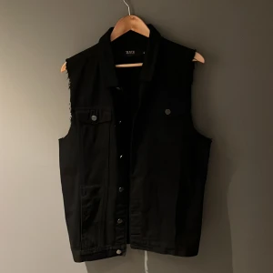 Svart jeans väst - Säljer en svart jeans väst från EMP som har knappt har användts. Har haft på mig den 1 gång för något år sen och har tidigare haft två tygmärken och 3 små pins på sig, kan möjligvis hitta små märken av gamla stygn men inget som påverkar västen. Orginal pris: 469kr