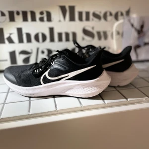 Svarta Nike sneakers - Snygga svarta Nike sneakers med vit sula och ikonisk swoosh-logga i vitt. Skorna har snörning och en modern design som passar perfekt för träning eller vardagsbruk. Köpta för 600kr💞