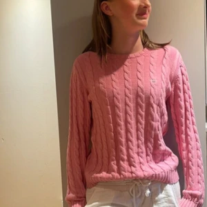 Rosa stickad tröja från GANT - Säljer en snygg rosa stickad tröja från GANT med kabelstickat mönster. Tröjan har långa ärmar och en rund halsringning. Perfekt för att vilja klä upp sig lite eller liknande