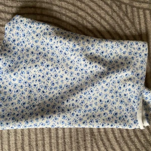 Blommig kjol i blått och vitt -  Väldigt fin kjol, Med fina blommor. Kjolen är inte kort men inte lång Den är Mittemellan. Har tyvärr råkat klippa bort lappen där jag köpt dem och storlek. Men kan gissa att det är runt s-xs