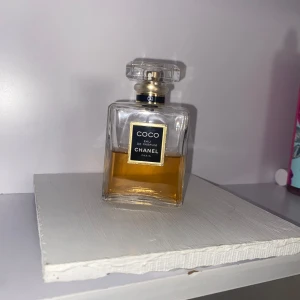 Coco Eau de Parfum från Chanel - Elegant och tidlös Coco Eau de Parfum från Chanel i en klassisk fyrkantig glasflaska med en stilren svart etikett. Parfymen har en gyllene färg och kommer med en dekorativ transparent kork. Perfekt för den som älskar lyx och sofistikation. Säljer den för ett otroligt pris eftersom den är gammal och använd, men det finns mycket kvar. Säljer den även för att jag har en annan.
