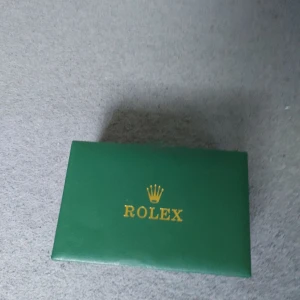  klocka med grön urtavla och två armand - Säljer en lyxig  klocka med grön urtavla, guldfärgade detaljer och tvåfärgad länk i silver och guld. Klockan levereras i originalbox och har klassisk design. Perfekt accessoar för dig som gillar exklusiva detaljer.