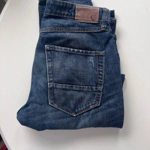 Blå jeans tapered - Snygga blå jeans med ”sliten” look och smal passform.