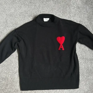 Svart stickad tröja från Ami - Säljer en svart stickad tröja från Ami med den klassiska hjärt broderingen. Tröjan är väldigt stilren, snygg och passar till vilken outfit som helst! Jag kan tyvärr inte verifiera äktheten på denna tröja eftersom jag köpte den på plick, därav det generösa priset. Annars är tröjan använd ett par gånger men utan några defekter. Hör av dig vid några frågor! Köparen står för frakt.