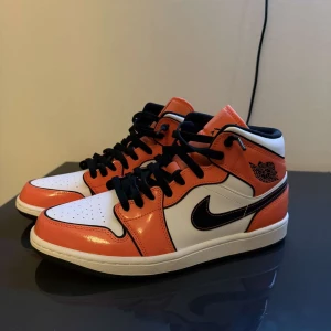 Nike Air Jordans orange och vita sneakers - Säljer ett par Nike Air Jordans sneakers i orange, vitt och svart. Skorna har klassisk svart swoosh, svarta skosnören och hög modell. Perfekta för dig som gillar streetwear och vill sticka ut med färg.