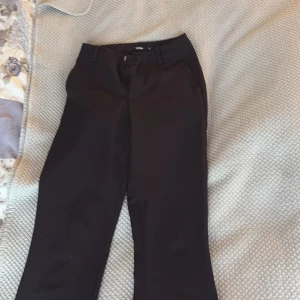 Svarta kostymbyxor från BikBok - Klassiska svarta kostymbyxor från BikBok med normal passform och raka ben. Byxorna har hällor för bälte och stängs med dragkedja och knapp. Perfekta till en stilren look.