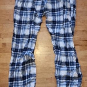 Rutiga pyjamasbyxor från Mywear - Mysiga rutiga pyjamasbyxor från Mywear i blått, vitt och grått. Byxorna har en klassisk passform och är perfekta för hemmakvällar. Tillverkade i mjukt bomullsmaterial för extra komfort.