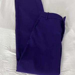 Lila kostymbyxor  - Snygga lila kostymbyxor. Byxorna har hällor i midjan och en bakficka med diskret söm. Perfekta för dig som vill sticka ut med färg. storlek XS från Lindex