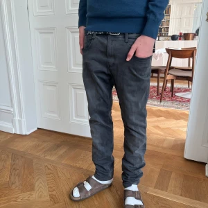 Replay anbass - Säljer ett par grå jeansbyxor med normal passform och klassisk femficksdesign. Byxorna har midwaist och raka ben, perfekt för en avslappnad stil. Passar till många olika tillfällen och är lätta att matcha med olika tröjor och skor.modellen är 170.W29 L 30