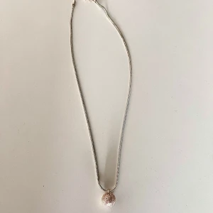 halsband  - Säljer ett stilrent halsband i silverfärg från Snö of Sweden. Halsbandet har en tunn kedja och en rund, strukturerad berlock som hänger nedtill. Perfekt för att ge en elegant touch till din outfit.