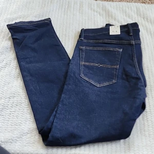 Mörkblå replay jeans W32 L28 - Snygga mörkblå jeans med klassisk femficksdesign och kontrastsömmar. Jeansen har normal passform och raka ben, perfekta till vardags. Materialet är slitstarkt denim och de har en enkel knappstängning i midjan.
