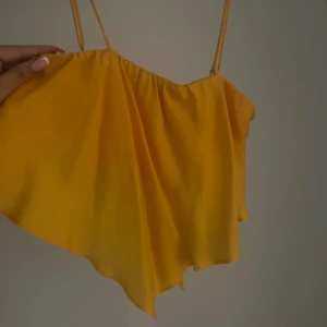 Gul oneshoulder topp - Säljer en orange topp med smala axelband. Endast använd en gång. 