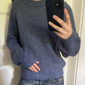 Blå stickad tröja från Object - Mysig blå stickad tröja från Object med rund halsringning och långa ärmar. Tröjan har en enkel och klassisk design, perfekt att matcha med jeans eller kjol. Materialet är mjukt och ger en avslappnad känsla. Använd ett par gånger.