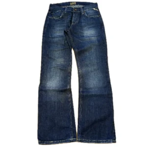 Blå bootcut jeans W30 - Säljer ett par klassiska blå jeans med bootcut passform. Jeansen har fem fickor, normal midja och snygga slitningar framtill. Perfekta för dig som gillar en lite vidare stil nertill.