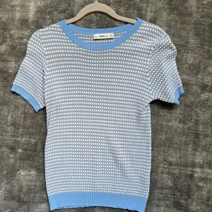 Blå och vit mönstrad topp från Zara - Säljer en söt topp från Zara i ljusblått och vitt med korta ärmar. Tröjan har ett tätt mönster och ribbade kanter