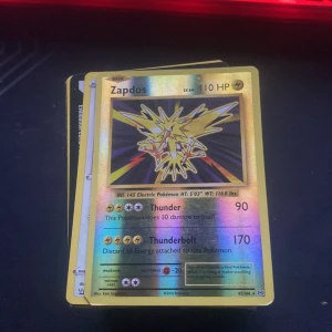 Zapdos - En glänsande samlarkort med den legendariska fågeln Zapdos från Pokémon. Perfekt för dig som gillar att samla, byta eller spela Pokémonkort. Kortet har en cool holografisk design och är en favorit bland fans av spelet och serien.