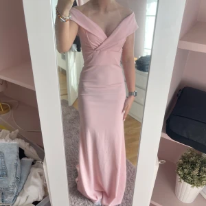 Ljusrosa långklänning med v-ringad offshoulder - Säljer en ljusrosa långklänning med bred v-ringad offshoulder-krage! Klänningen är ganska stretchig så passar i flera storlekar. Säljer denna då jag inte har användning av denna. Perfekt balklänning!💕